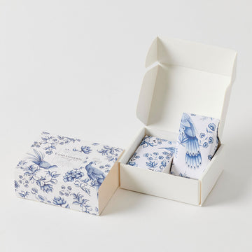 A blue and white box illustrated with birds and flowers and the text 'Chinoiserie French Linen Scent' in a box in the middle.