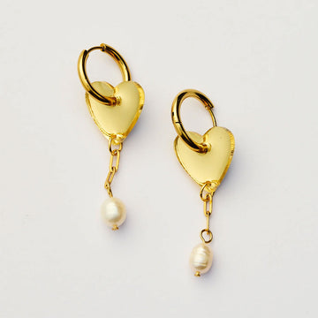 Gold heart-shaped earrings with pearl drops on a light gray background.