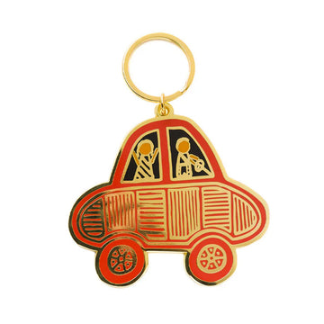 An enamel keyring shaped like a car with two people inside.
