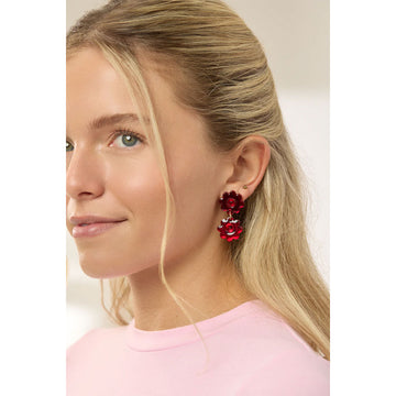 Red flower-shaped earrings on a light gray background.