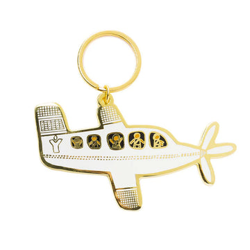 An enamel keyring shaped like a plane with people inside.