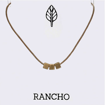 Necklace with gold cube pendants on a light gray background, featuring the brand 'RANCHO'.