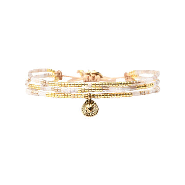 Stack of gold and beige beaded bracelets with a charm on a white background.