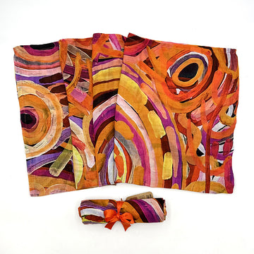A baby swaddle pictured printed with artwork by Cedric Varcoe in shades of orange and brown. There is also a baby swaddle wrapped up.