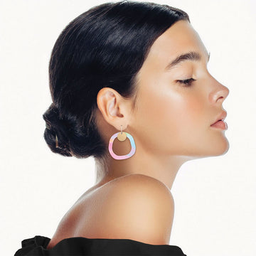 A pair of circle shaped drop earrings with an outline printed with artwork by Maggi McDonald.