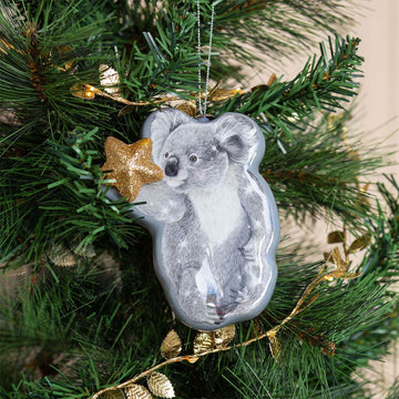 A koala shaped Christmas ornament holding a gold star.