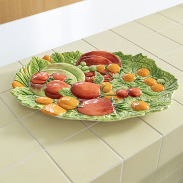 Decorative ceramic plate with fruit design on a light gray background.