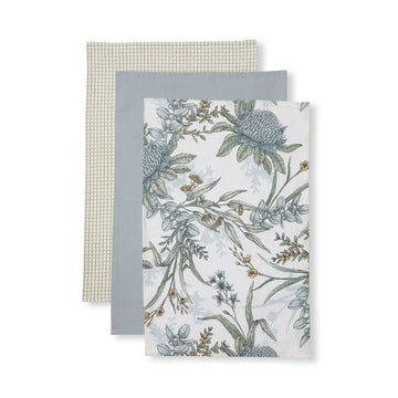 Three tea towels layered on top of each other. The back tea towel has a grid pattern, the middle tea towel is plain grey and the top tea towel has a floral print.