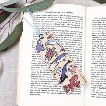 A wooden bookmark illustrated with marine animals is resting over an open book.