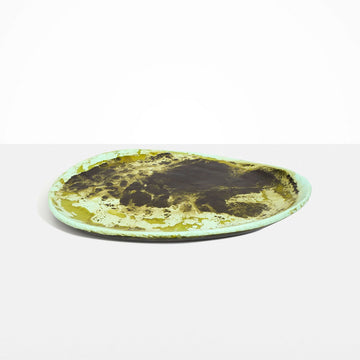 An irregular shaped round platter made from green resin.