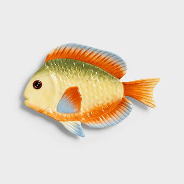 Decorative fish-shaped plate with orange, yellow, and blue colors on a light gray background.