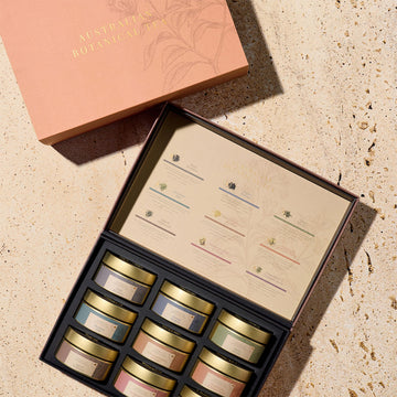 An open box with nine round containers inside and a list on the inner lid of the tea inside.