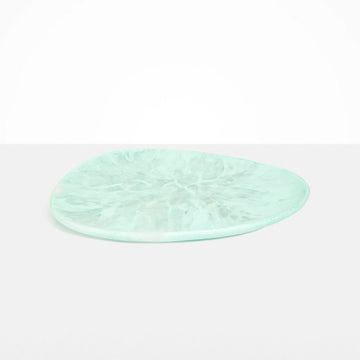 An irregular shaped round platter in mint green resin.