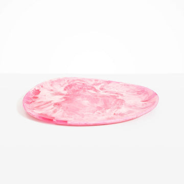 An irregular shaped round platter in pink resin.