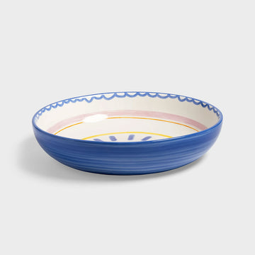 Side view of a blue ceramic bowl with decorative rim on a light gray background.