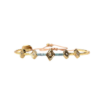 A gold and blue beaded bracelet with diamond-like stones on a white background
