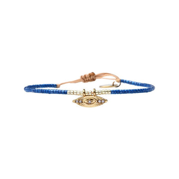 Bracelet with blue beads and gold evil eye charm on a white background.