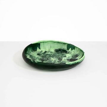 A large round shallow bowl in dark green resin.