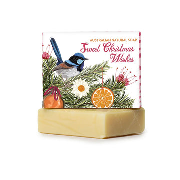 A bar of soap with a wrapped bar of soap on top. The wrapping has the text 'Australian Natural Soap Sweet Christmas Wishes' and an illustration of a fairy wren and flowers.