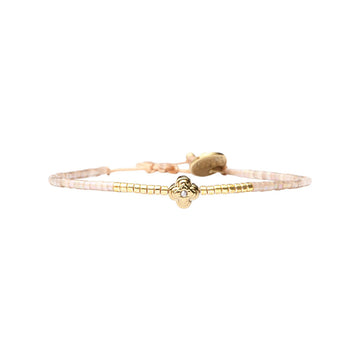 A white and gold beaded bracelet with a gold flower charm.