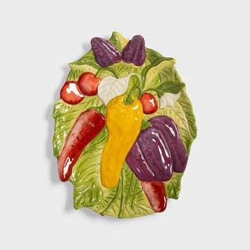Decorative plate with colorful peppers and tomatoes on a white background