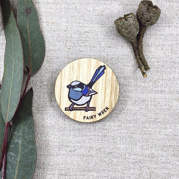 A round wooden magnet illustrated with a fairy wren and gum leaves in the background.