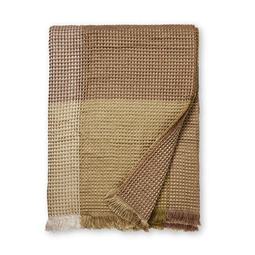 A folded up throw with a waffle pattern and printed with large checks in shades of brown.