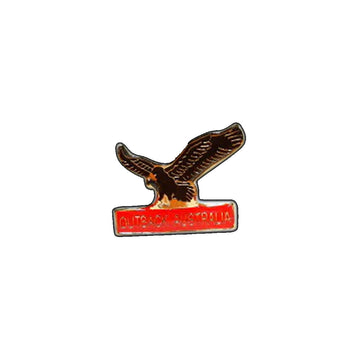 A hat badge shaped like an eagle with a red bar underneath.