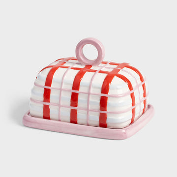 Ceramic butter dish with red and white striped lid on a light gray background.