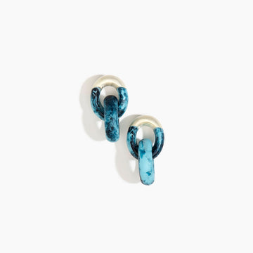 A pair of earrings made up of two hoops intertwined made from blue resin.