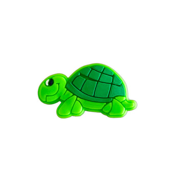 Green turtle-shaped shoe charm made from PVC on a white background.