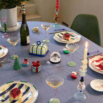 Four round ceramic plates with colorful diagonal stripe patterns on a light gray background.