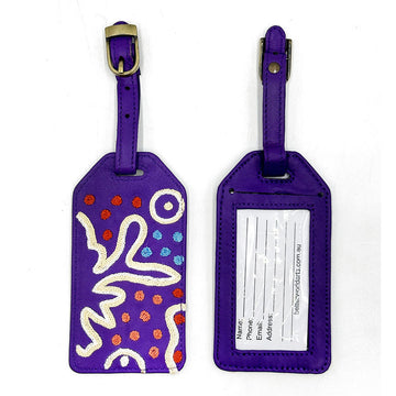 Two luggage tags pictured, showing the front and back. The front is embroidered with artwork by Paddy Stewart and the back has personal information to fill in.