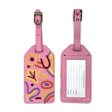 Two luggage tags pictured showing the front and back. The front is embroidered with artwork by Cedric Varcoe and the back has personal information to fill in.
