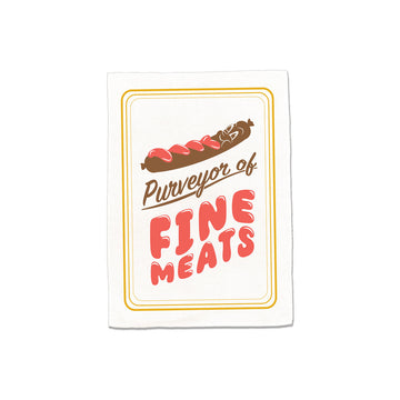 Tea towel with 'Purveyor of Fine Meats' text and graphic of a sausage with a face on a white background.