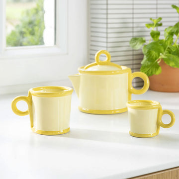 Two yellow ceramic mugs on a light gray background.