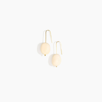 Pair of earrings with cream resin stones on a white background.