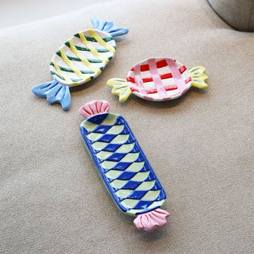 Decorative candy-shaped plate with blue and yellow design on a light gray background.