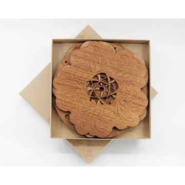 A stack of flower shaped wooden placemats in a square box.