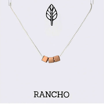 Necklace with rose gold geometric pendants on a white background with 'RANCHO' branding.