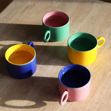 Four colorful mugs (blue, pink, yellow, green) on a light gray background.