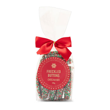 A clear bag filled with speckled chocolate in Christmas colours tied with a red bow.