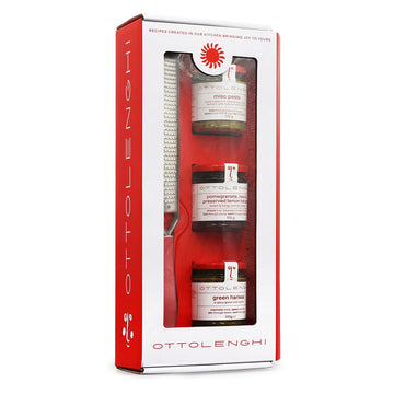 A gift set of three jars of spreads and a grater in a red and white box with a clear window.