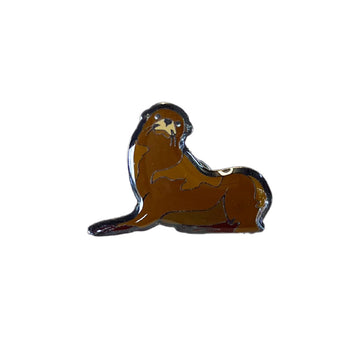 An enamel pin shaped like a seal.