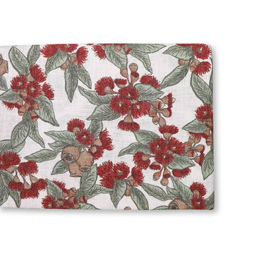 Floral patterned fabric with red flowers and green leaves on a white background.