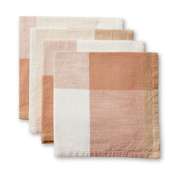 A set of four linen napkins folded and layered on top of each other printed with a rust brown checkered pattern.