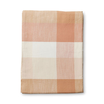 A folded up table cloth printed with a rust check pattern.