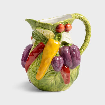 Ceramic pitcher with embossed vegetable design on a white background.