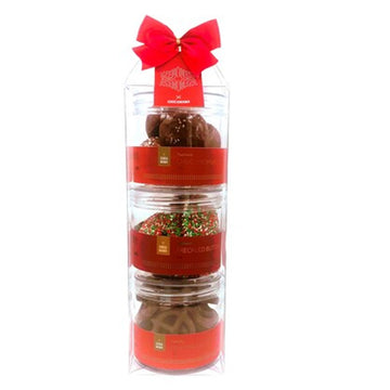 Three clear containers filled with different chocolates stacked on top of each other with a red bow at the top.