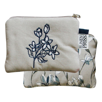 Front and back view of a purse embroidered with magnolia flowers on the front and printed with magnolias on the back.